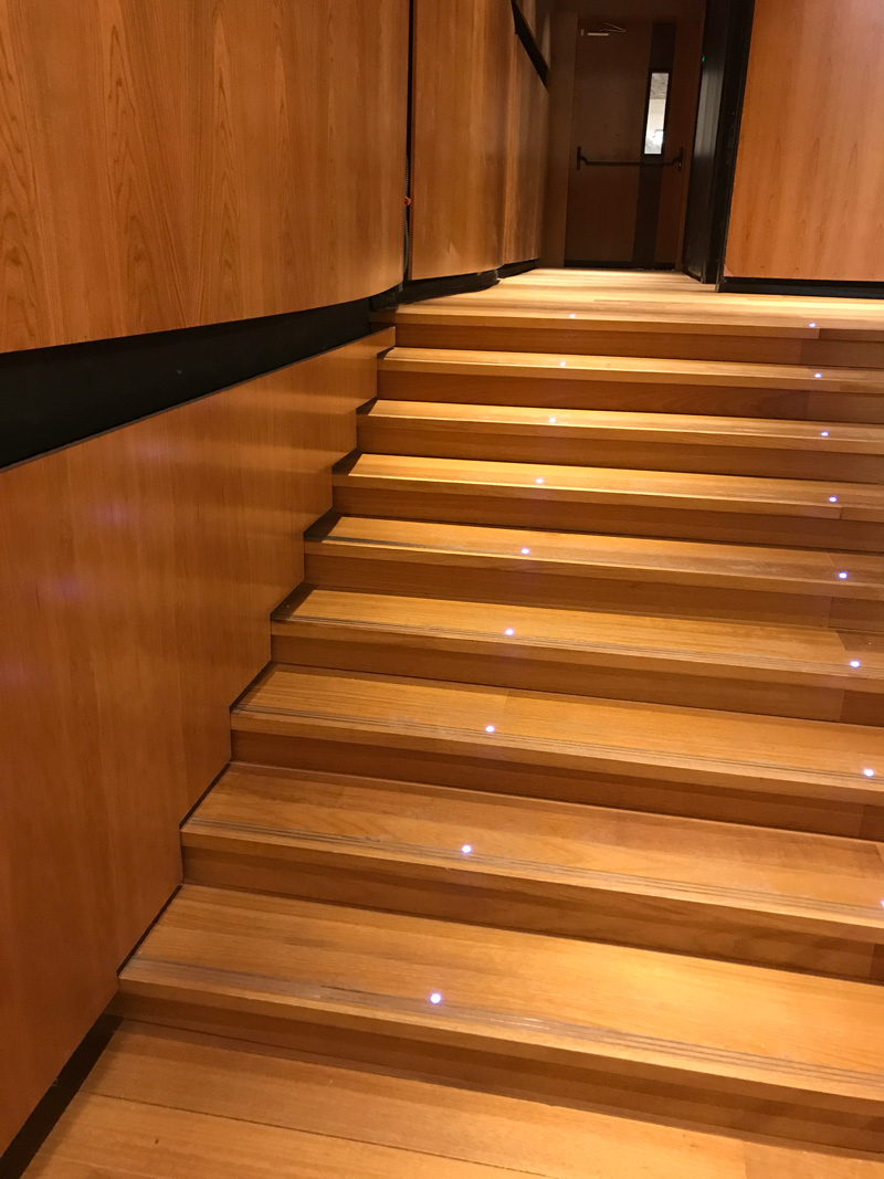 מדרגות מחופות בפרקט מלא מעץ אירוקו כולל תאורה שקועה ופסי התרעה מנירוסטה 