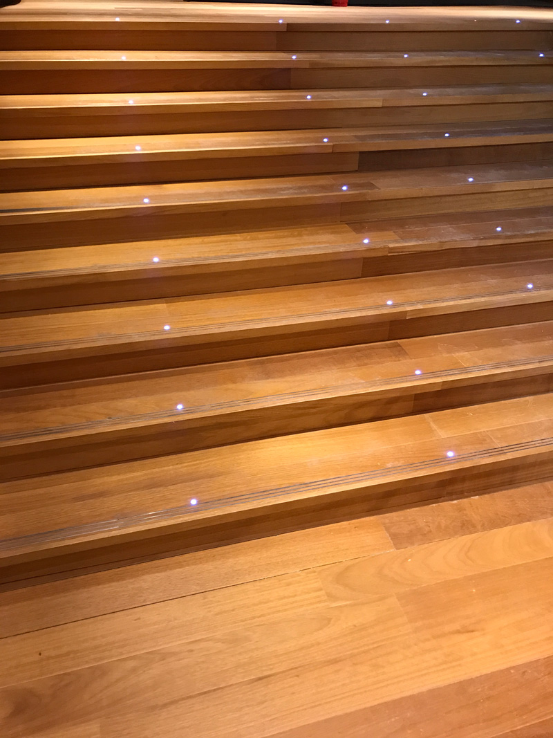 מדרגות מחופות בפרקט מלא מעץ אירוקו כולל תאורה שקועה ופסי התרעה מנירוסטה 
